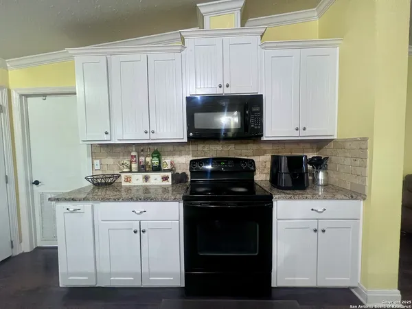 a kitchen with white cabinets and black appliances