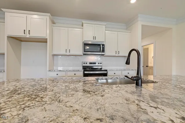 a kitchen with granite countertop a stove a sink and a microwave