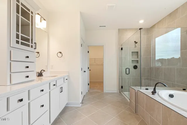 a large bathroom with a double vanity sink a large mirror and a bathtub