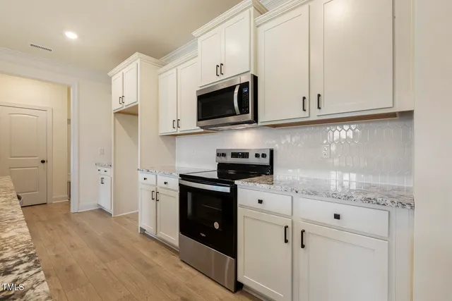 a kitchen with stainless steel appliances granite countertop white cabinets and a stove