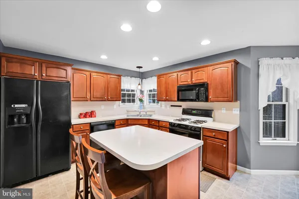 a kitchen with stainless steel appliances a stove a refrigerator a sink a stove a dining table and chairs with wooden floor
