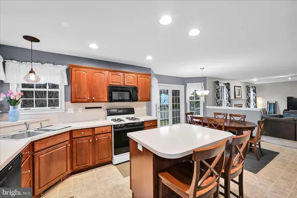 a kitchen with stainless steel appliances granite countertop a stove a sink dishwasher a dining table and chairs with wooden floor