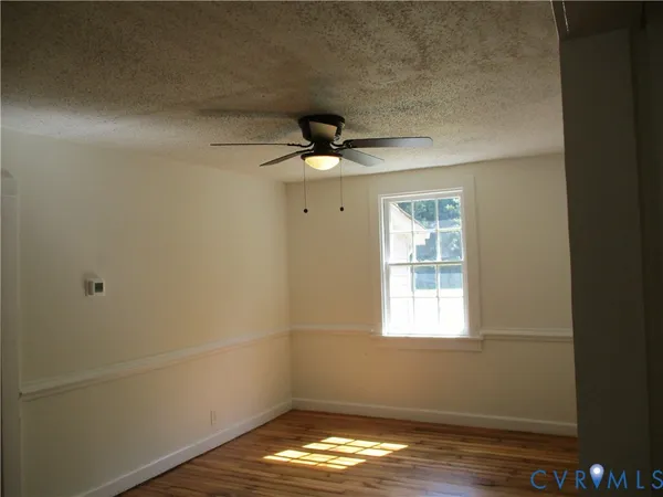 a view of empty room with wooden floor and fan