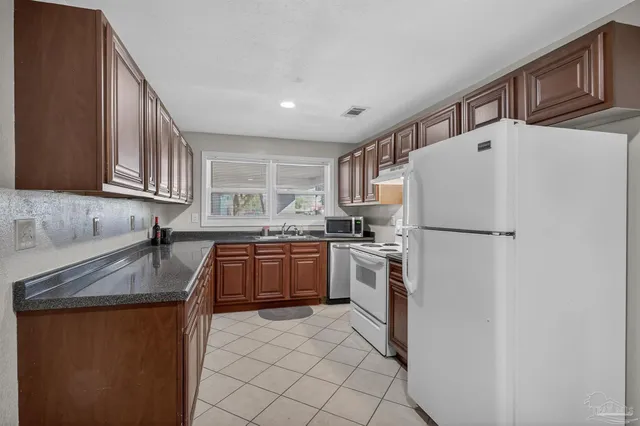 a kitchen with stainless steel appliances granite countertop a refrigerator and a stove top oven