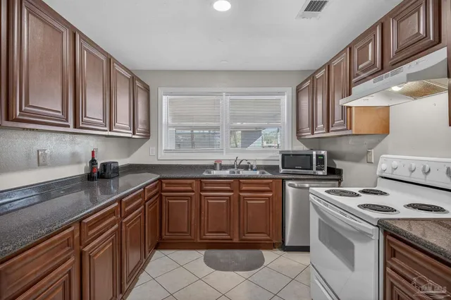 a kitchen with stainless steel appliances granite countertop a sink and a refrigerator