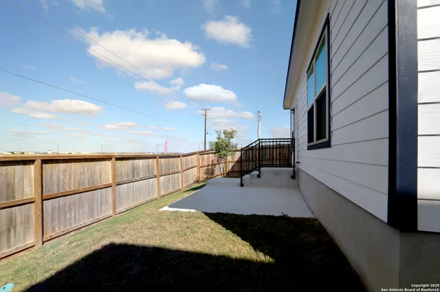 a view of a backyard with plants and wooden fence