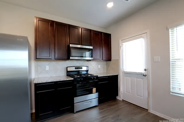 a kitchen with granite countertop wooden cabinets and stainless steel appliances