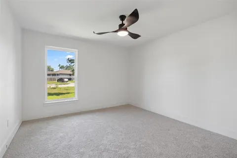 an empty room with window and ceiling fan