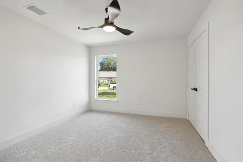 an empty room with windows and ceiling fan