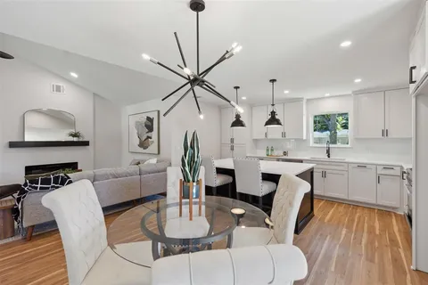 a kitchen with stainless steel appliances kitchen island granite countertop a dining table chairs and a refrigerator