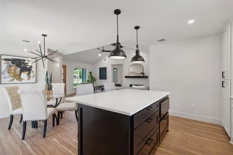 a view of a dining room and livingroom with furniture wooden floor a chandelier