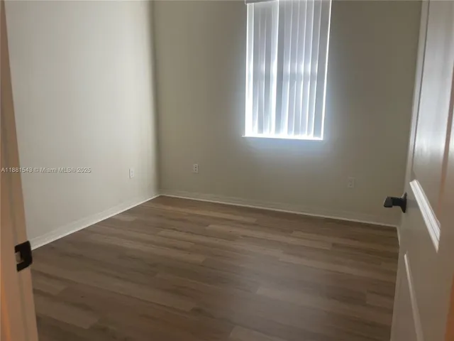 an empty room with wooden floor and windows in it
