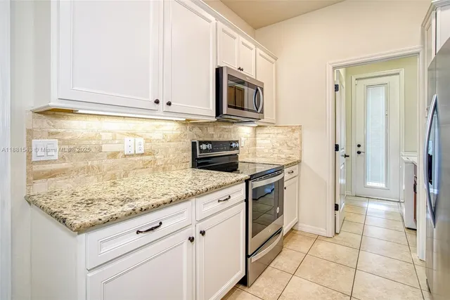 a kitchen with stainless steel appliances granite countertop a stove a sink and a microwave