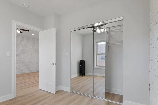 a view of an empty room with wooden floor and a bathroom