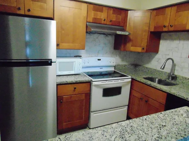 a kitchen with stainless steel appliances granite countertop a refrigerator sink and cabinets