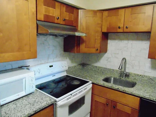 a kitchen with granite countertop a sink a stove and cabinets