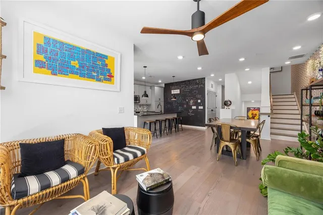 a kitchen with stainless steel appliances kitchen island granite countertop a refrigerator a stove a sink a dining table and chairs with wooden floor