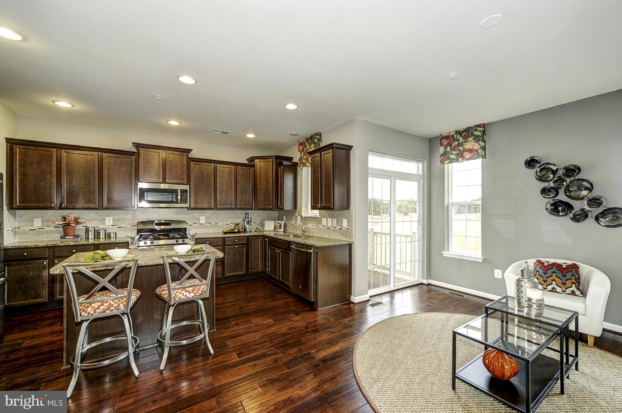 1003 Red Clover Road Gambrills, MD 21054 - Photo 4 of 30 a kitchen with stainless steel appliances granite countertop a stove top oven a sink a dining table and chairs with wooden floor