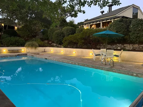 a view of a swimming pool with lawn chairs under an umbrella