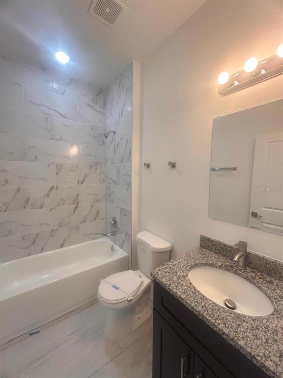 9451 North Emellia Avenue Citrus Springs, FL 34433 - Photo 17 of 24 a bathroom with a granite countertop sink a toilet a mirror a bathtub and shower
