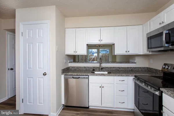 a kitchen with stainless steel appliances granite countertop a sink stove and microwave