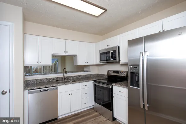 a kitchen with stainless steel appliances granite countertop a refrigerator sink and stove