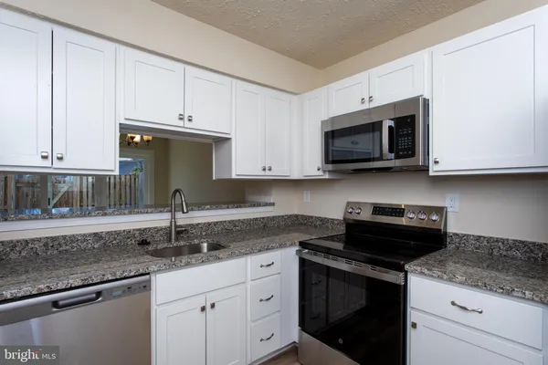 a kitchen with stainless steel appliances granite countertop white cabinets granite counter tops and a stove
