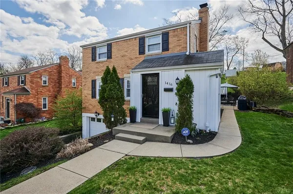 a view of a house with brick walls and a yard with plants