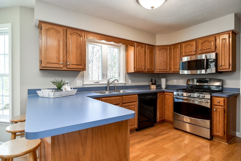 16 Russet Hill Road Ashland, MA 01721 - Photo 11 of 30 a kitchen with stainless steel appliances granite countertop wooden cabinets a stove top oven a sink and dishwasher with wooden floor