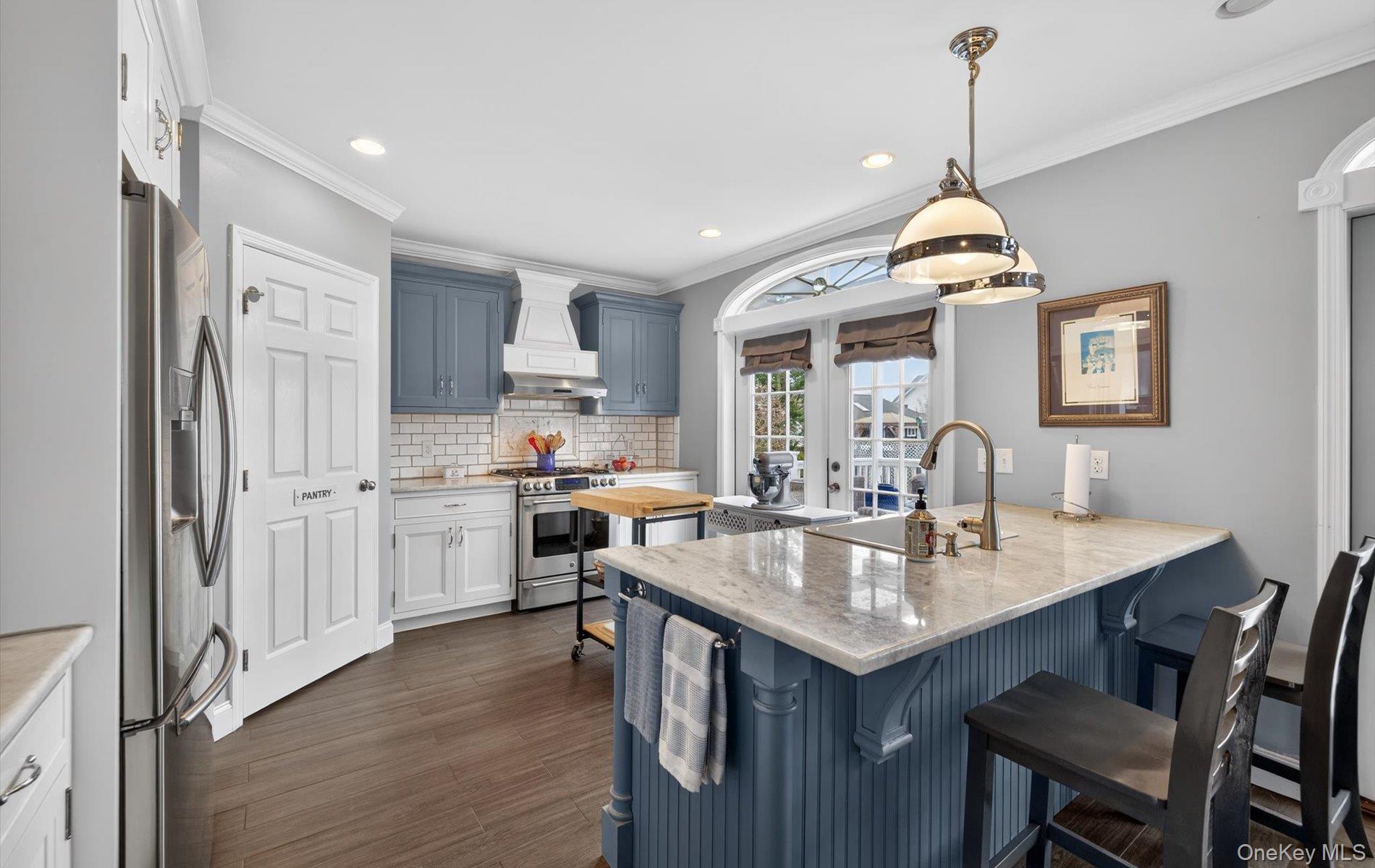 108 Awixa Avenue Bay Shore, NY 11706 - Photo 8 of 47 Dual tone kitchen with a breakfast bar area, a peninsula, light stone counters, stainless steel appliances, and decorative light fixtures