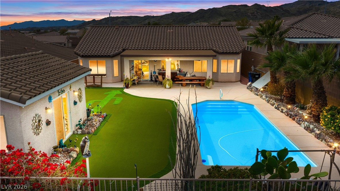 2516 Morrow Ridge Place Laughlin, NV 89029 - Photo 1 of 93 Back of house at dusk featuring a mountain view, stucco siding, a fenced backyard, and a patio