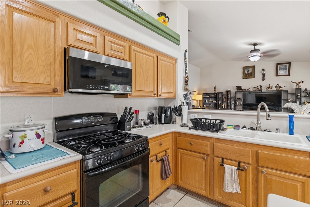 2516 Morrow Ridge Place Laughlin, NV 89029 - Photo 20 of 93 Kitchen featuring black gas stove, light countertops, stainless steel microwave, a ceiling fan, and light tile patterned flooring