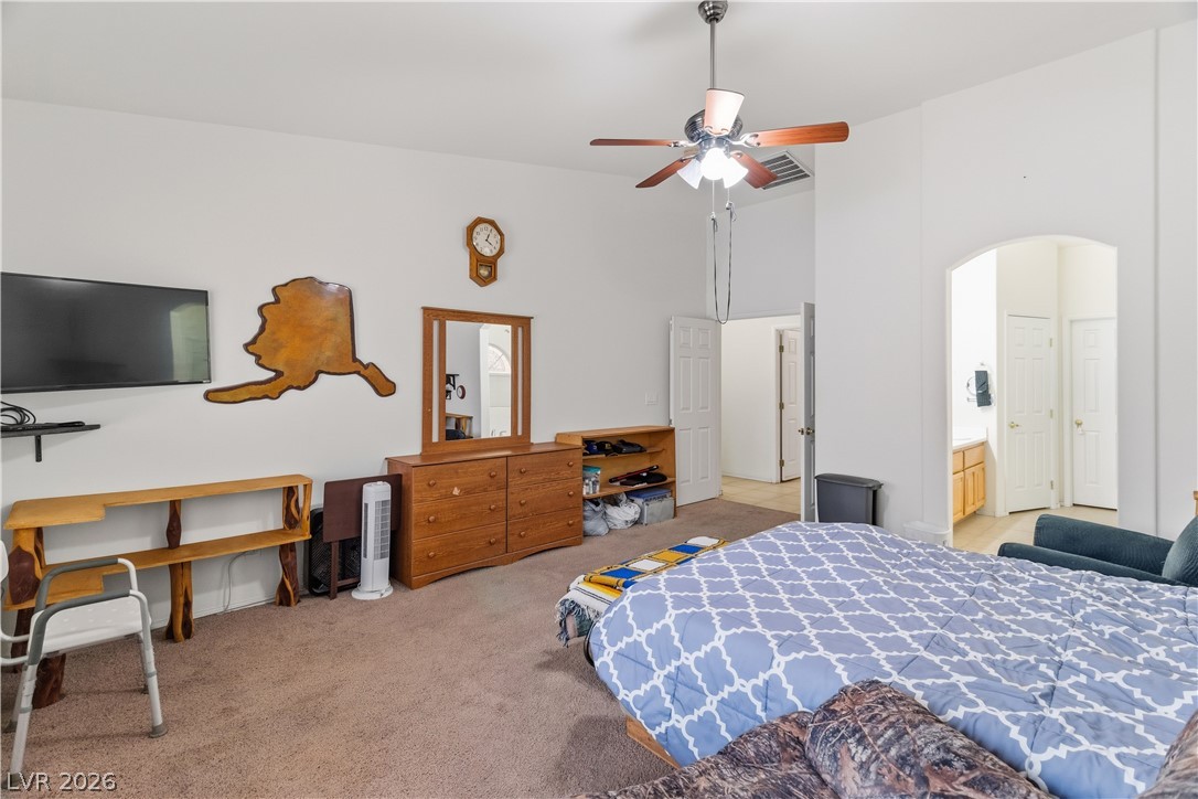 2516 Morrow Ridge Place Laughlin, NV 89029 - Photo 26 of 93 Primary Bedroom with light carpet, arched walkways, a high ceiling, ceiling fan, and ensuite bathroom