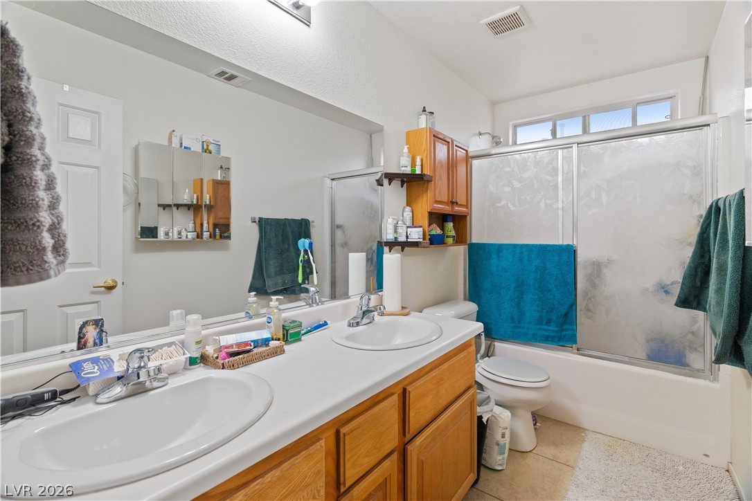 2516 Morrow Ridge Place Laughlin, NV 89029 - Photo 34 of 93 Hall Full Bathroom with double vanity, combined bath / shower with glass door, and light tile patterned floors