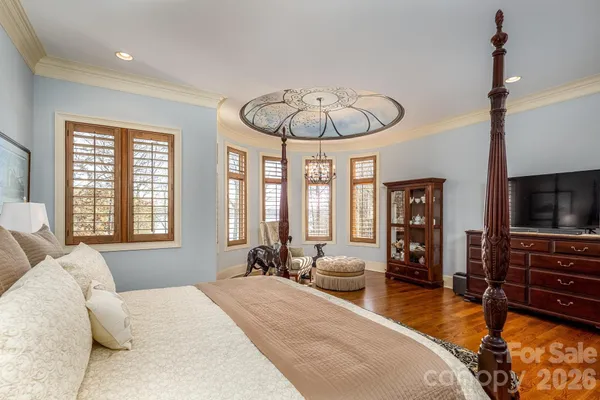a spacious bedroom with a bed a chandelier and a flat screen tv