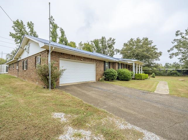 660 Hinton Road Counce, TN 38326 - Photo 3 of 40 Brick exterior with a blue metal roof, an attached two-car garage, a covered front porch, and a paved driveway