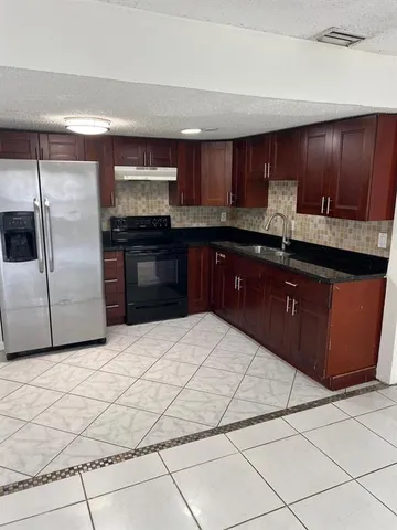 a kitchen with granite countertop a refrigerator and a stove top oven