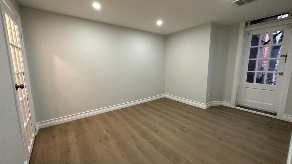 147 Winthrop Road, Unit 2 Brookline, MA 02445 - Photo 11 of 19 an empty room with wooden floor and windows