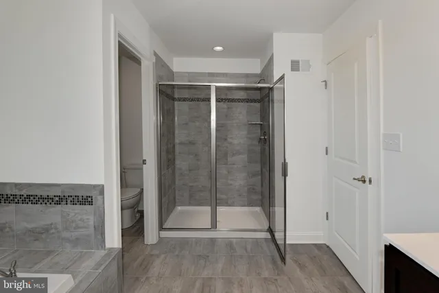 a spacious bathroom with a double vanity sink a toilet and a mirror