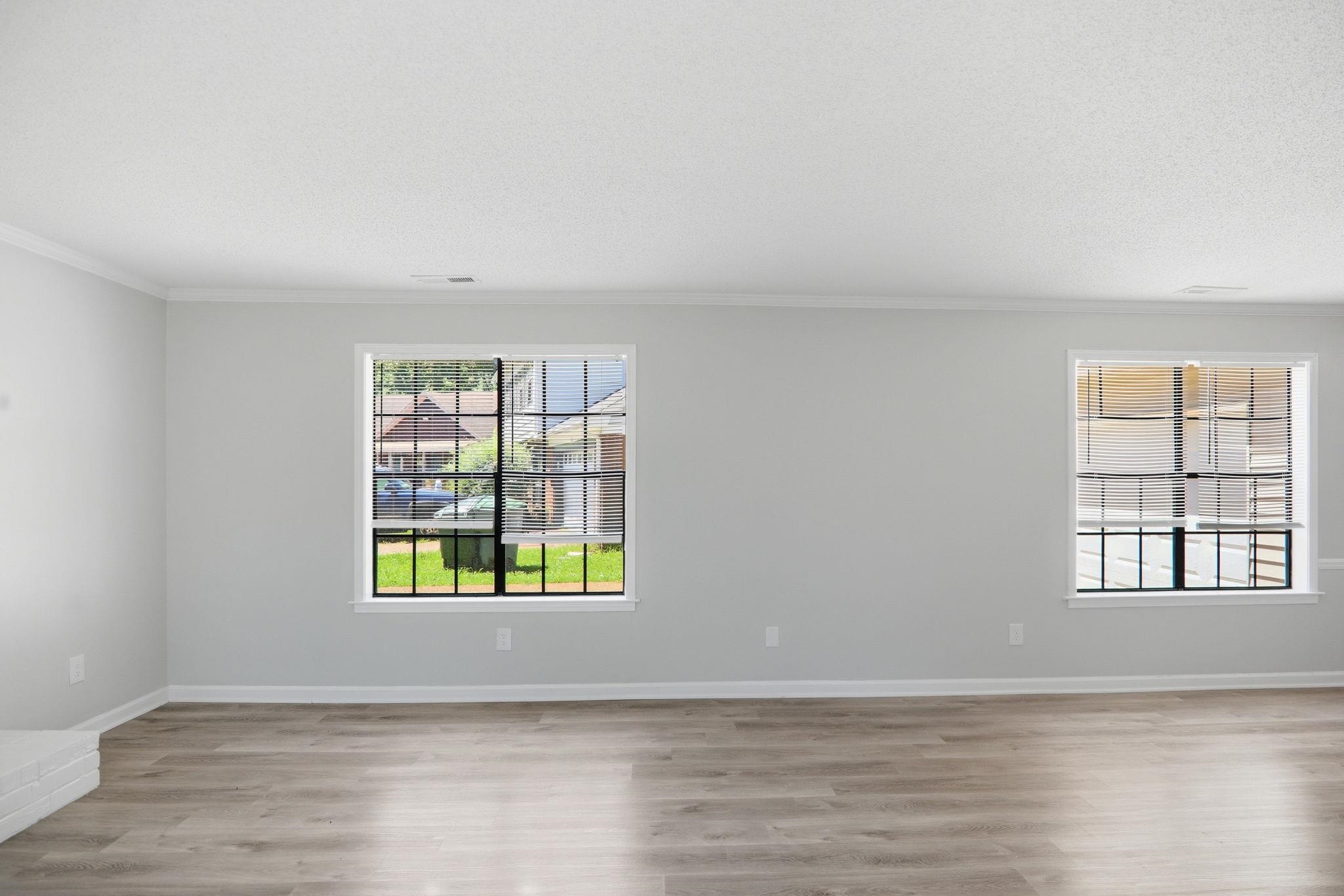 3113 Raleigh Ridge Cove Memphis, TN 38128 - Photo 6 of 38 Spacious room featuring wood-finish flooring, light grey painted walls, white crown molding, and two windows with black grilles