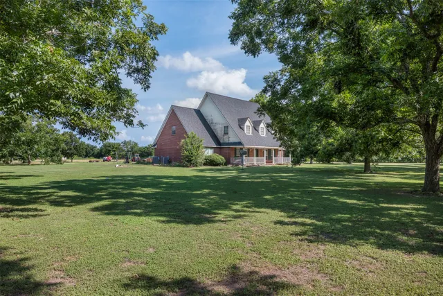 a view of a big house with a big yard and large trees