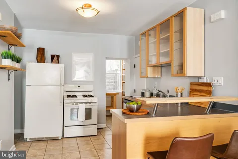 a kitchen with stainless steel appliances a refrigerator a sink a stove and white cabinets
