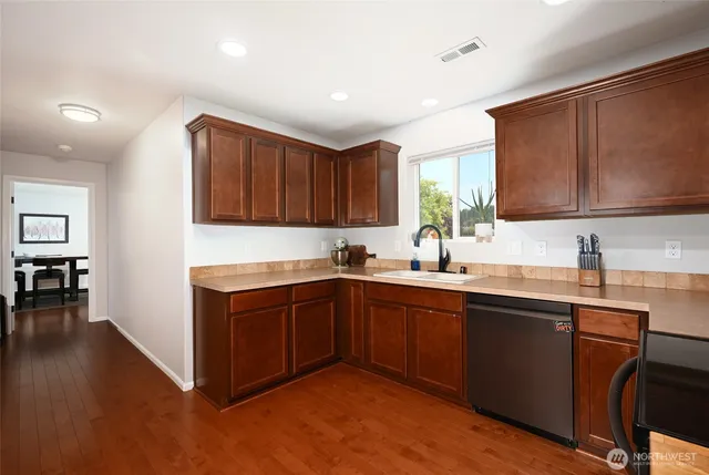 a kitchen with stainless steel appliances granite countertop wooden cabinets a stove top oven a sink and dishwasher with wooden floor