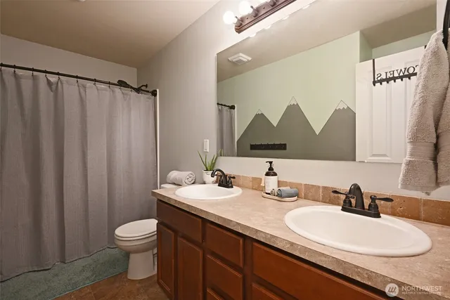 a bathroom with a double vanity sink toilet and a mirror