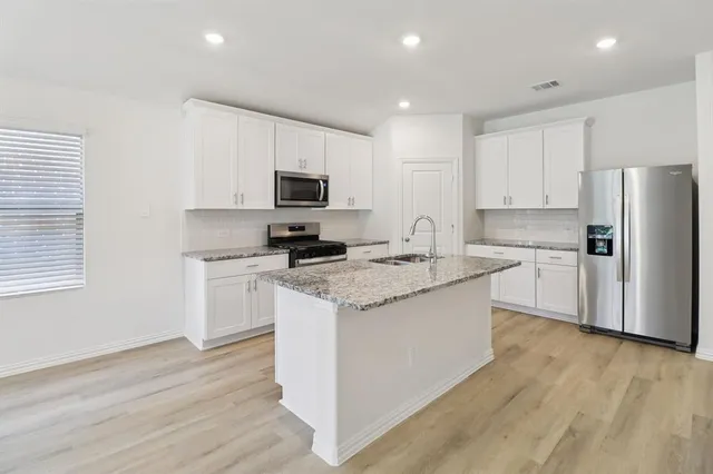 a kitchen with kitchen island granite countertop white cabinets and stainless steel appliances
