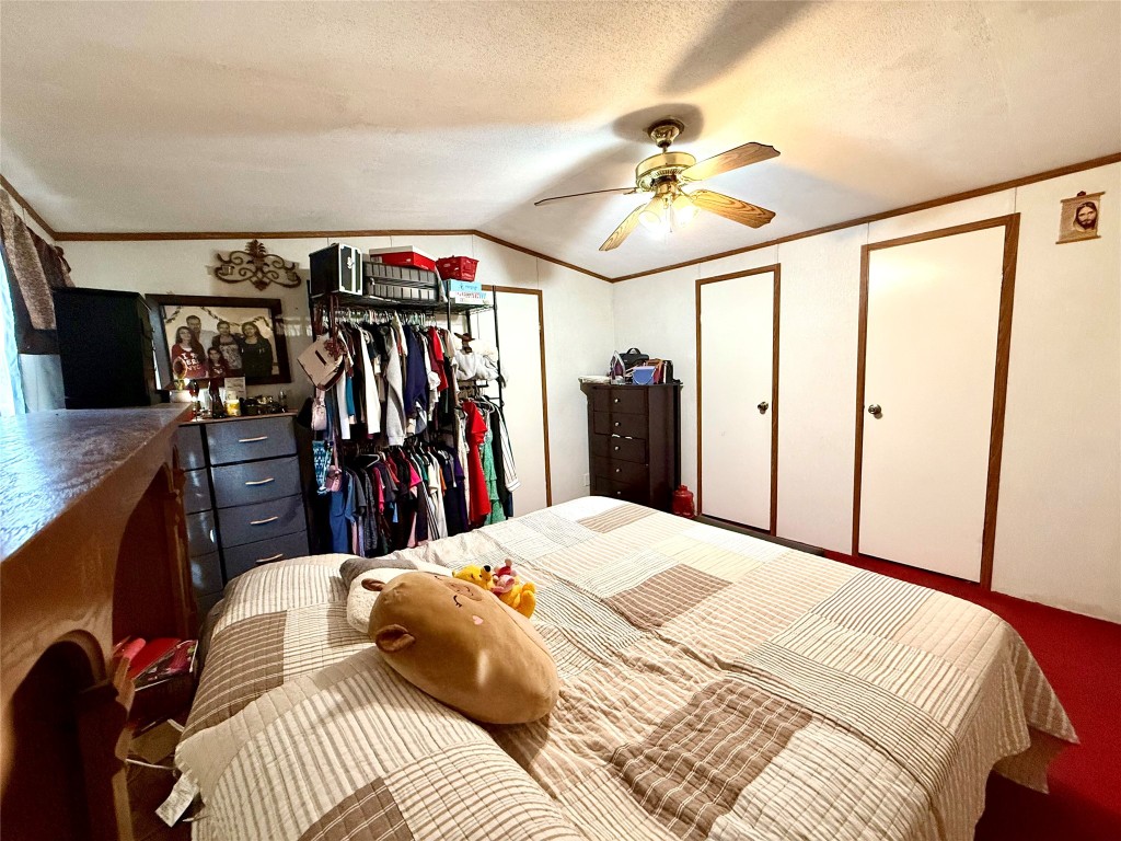 685 Fox Lane Lockhart, TX 78644 - Photo 37 of 39 Bedroom with a closet, ornamental molding, vaulted ceiling, ceiling fan, and a textured ceiling