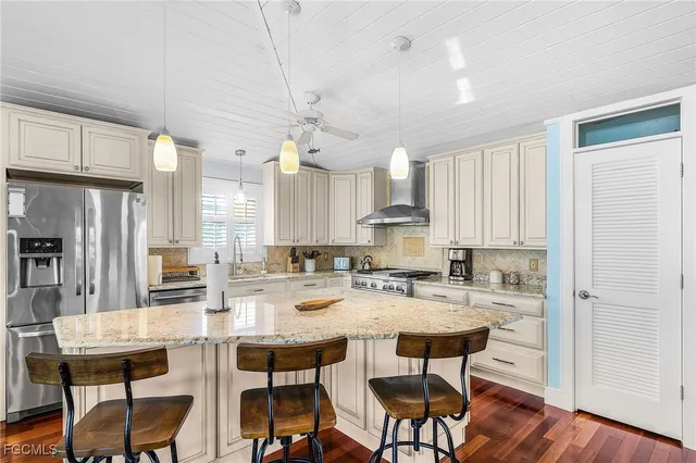 a kitchen with stainless steel appliances kitchen island granite countertop a dining table chairs and white cabinets