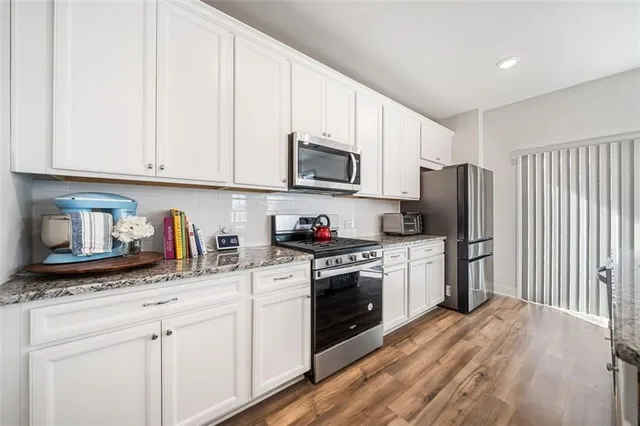 a kitchen with granite countertop white cabinets and stainless steel appliances