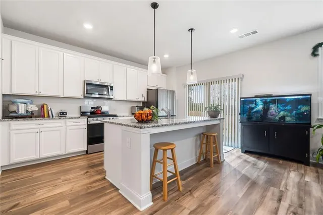 a kitchen with kitchen island granite countertop a sink a counter top space stainless steel appliances and cabinets