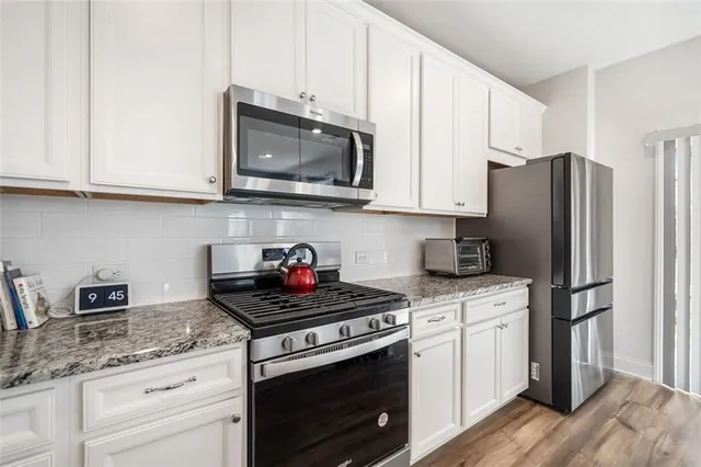 a kitchen with stainless steel appliances granite countertop white cabinets a stove a sink and dishwasher